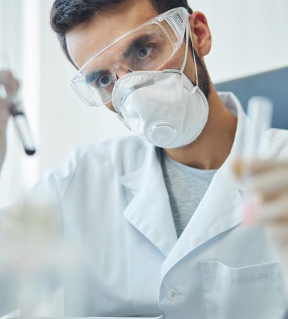 Biochemist examining biological substances in a laboratory Portrait of a virologist holding a pair of test tubes with reagents in his hands